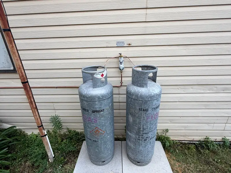 Two LPG gas cylinders standing on new pavers with a new regulator and copper gas line