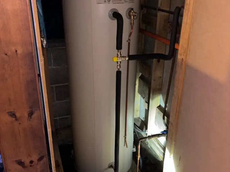 New electric hot water storage unit installed in a cupboard with insulated pipe connections