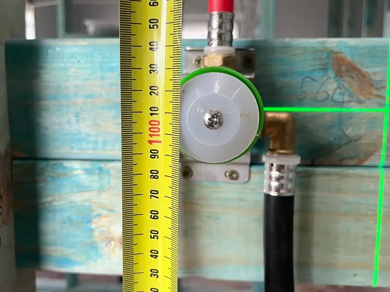 Mixer valve body fixed to timber framing beside a tape measure during a bathroom rough-in