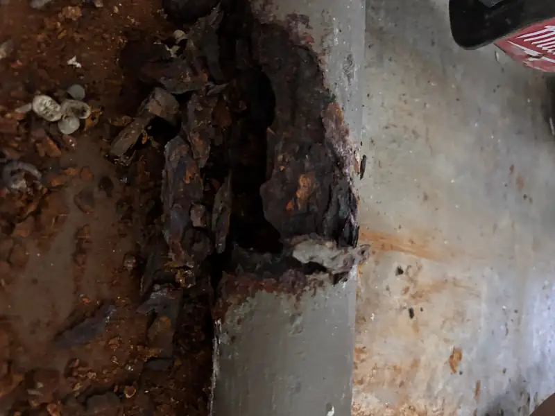 Close-up of an old corroded section of pipe exposed during a plumbing repair