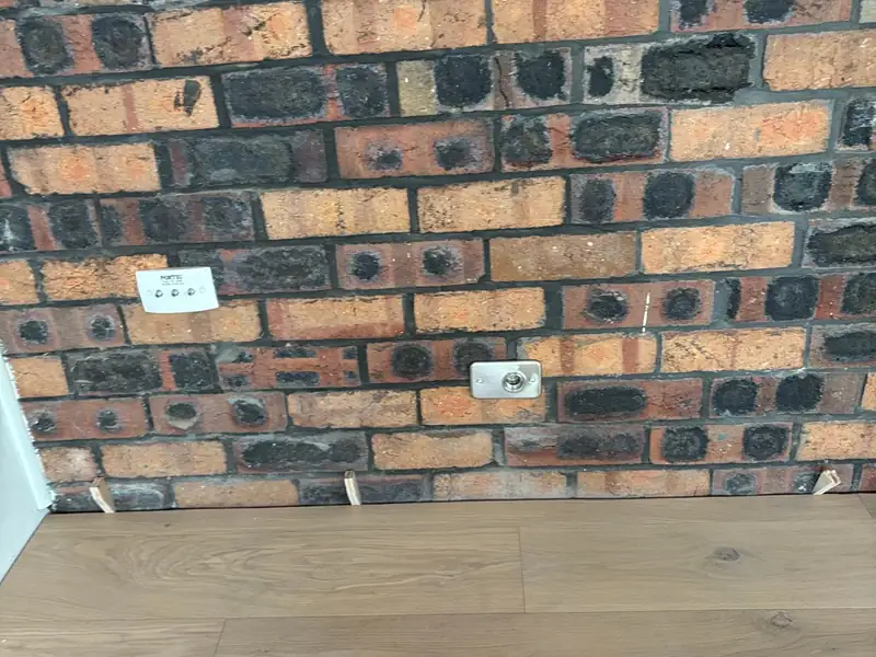 Gas bayonet fitting plate on an interior brick wall just above a timber floor