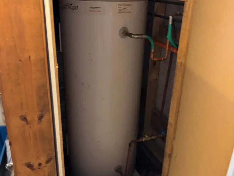Old hot water storage unit in a cupboard before it was replaced