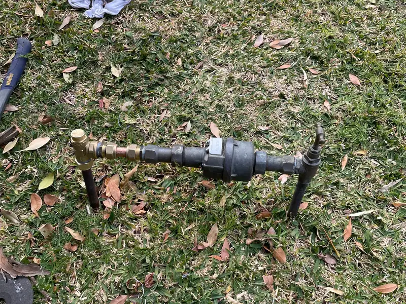 Water meter assembly with a new brass valve fitted, sitting at ground level on a lawn