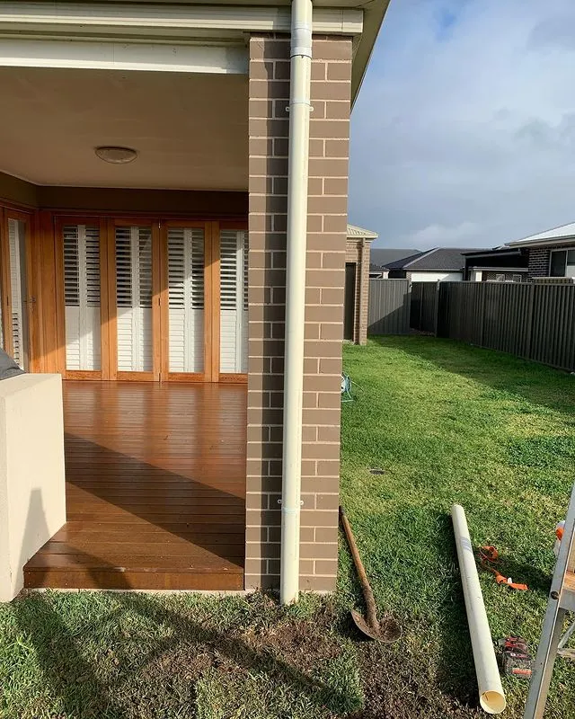New downpipe and drainage installed beside a home