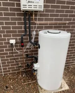 Gas instantaneous hot water unit and storage tank installed on a brick wall