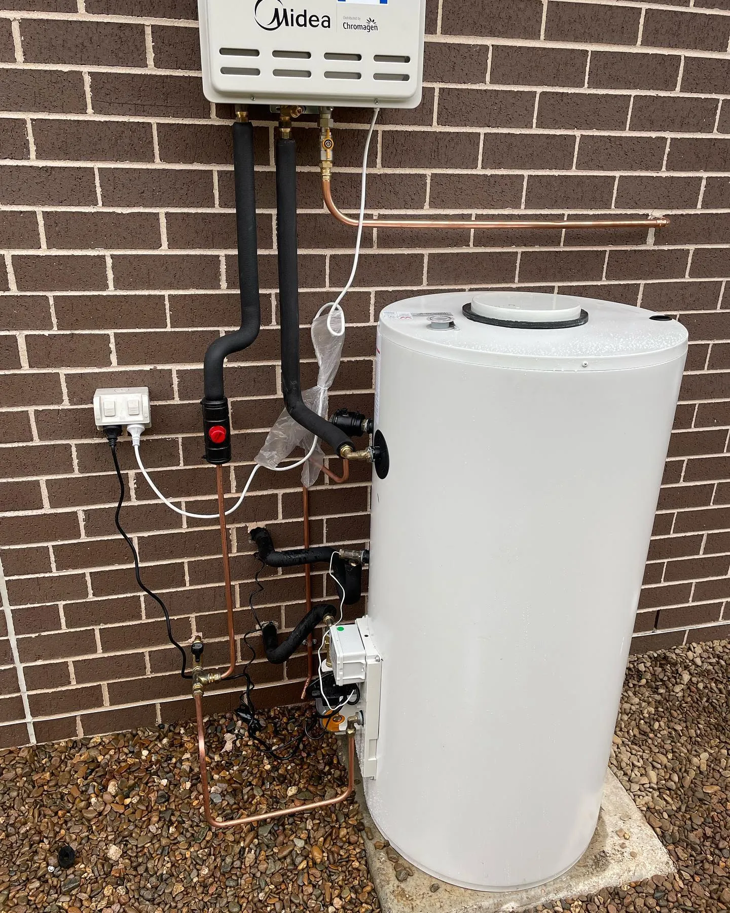 Gas instantaneous hot water unit and storage tank installed on a brick wall