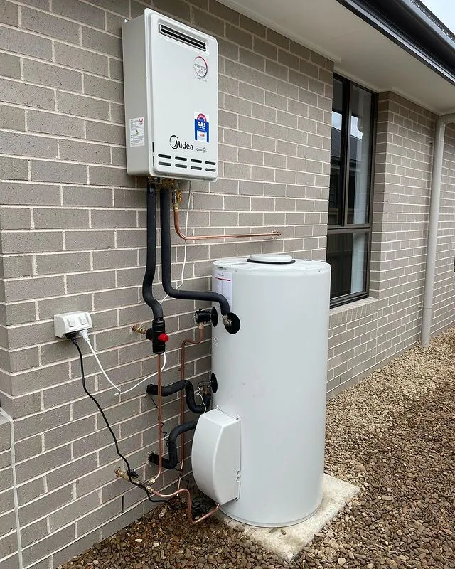 Gas instantaneous hot water unit and storage tank installed on a brick wall