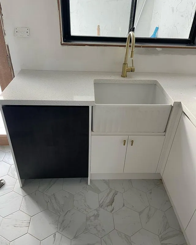 New laundry with a white farmhouse sink, brass tap and white cabinetry