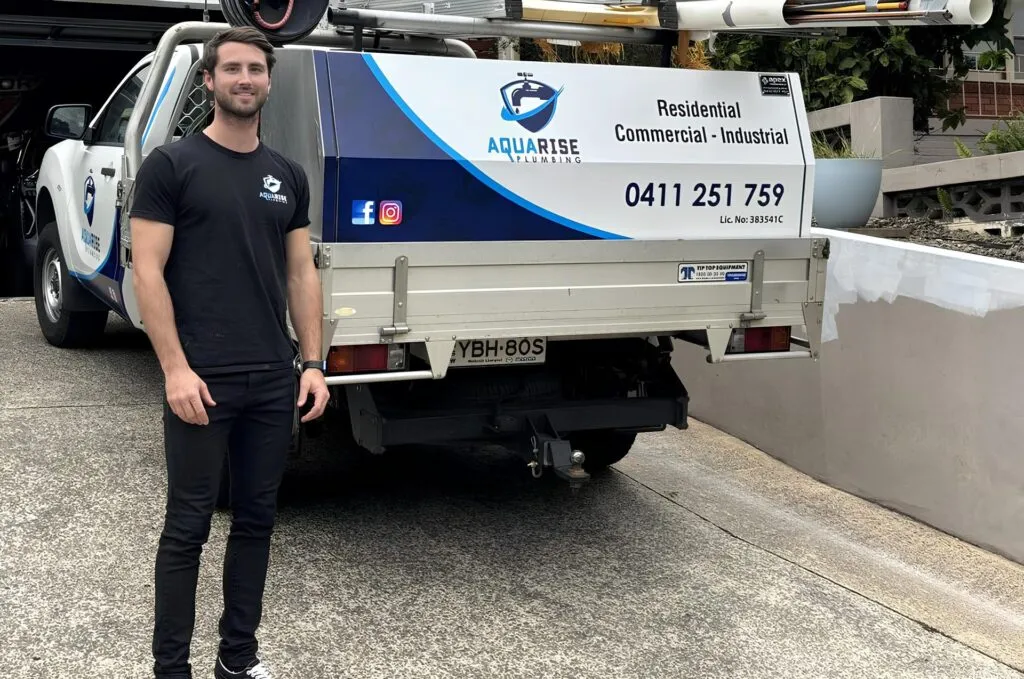 Aqua Rise Plumbing plumber standing beside the signwritten company ute