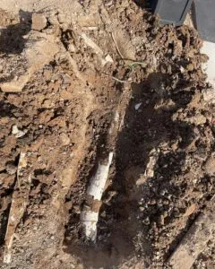 Excavated trench exposing a broken underground pipe