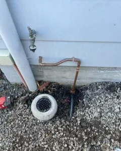 New copper pipework and a stormwater grate installed beside a house