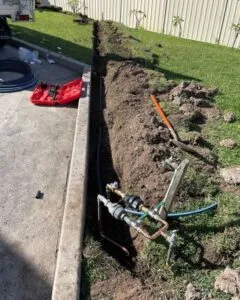Trench dug beside a driveway for new water pipework