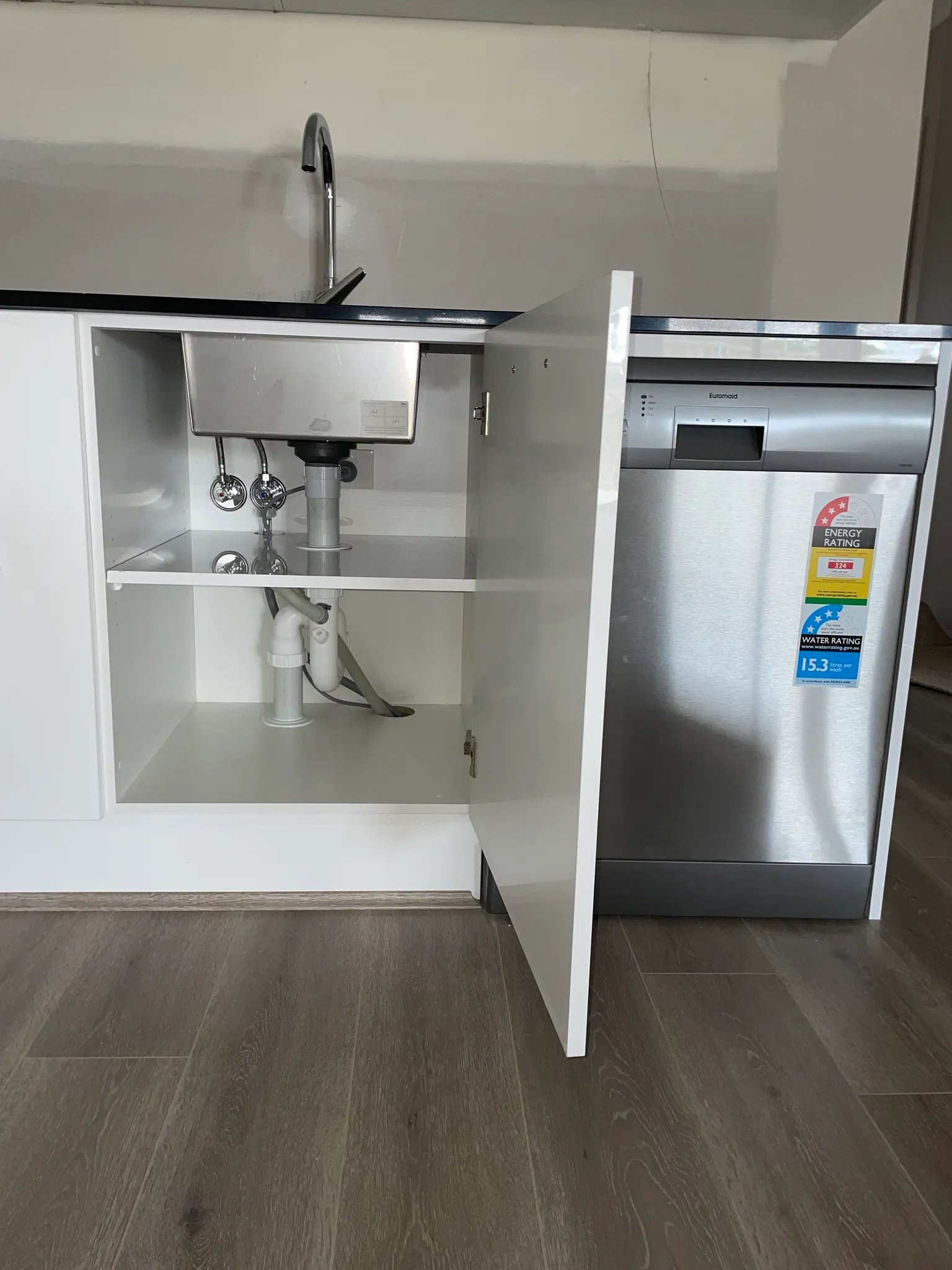 Kitchen sink cabinet with new plumbing and an installed dishwasher