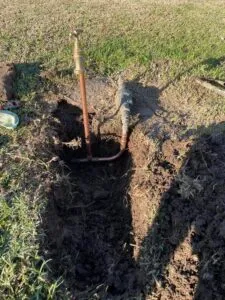 Hole excavated in a lawn exposing a copper water pipe