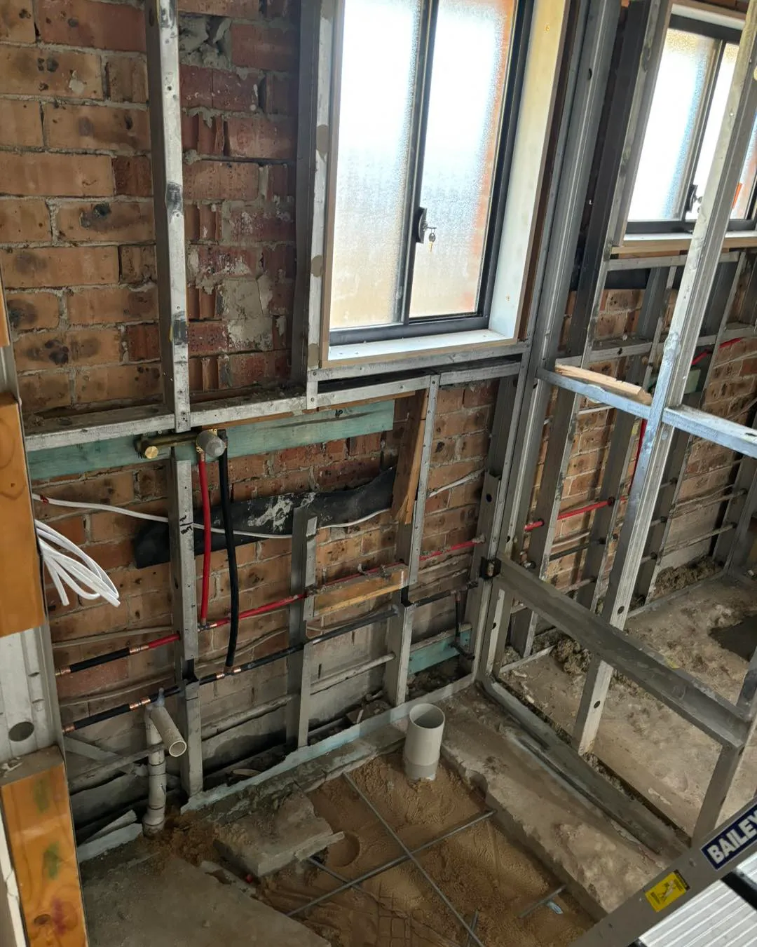 Bathroom wall framing opened up with new pipework roughed in